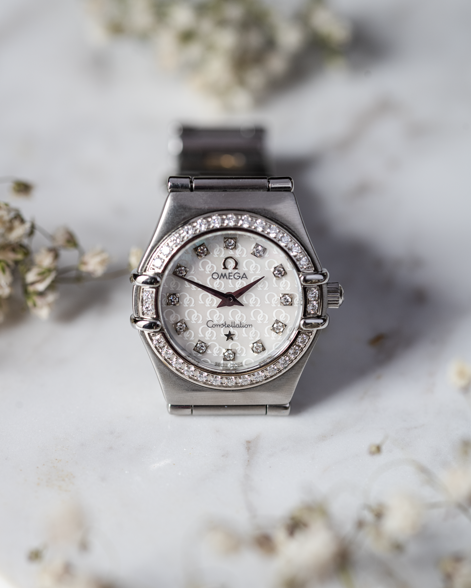 a ladies omega constellation photographed on a marble base with flowers