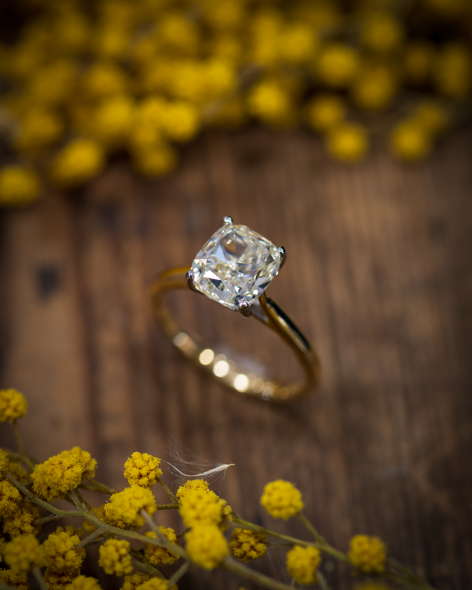 Large Oval Old Cut Diamond Solitaire photographed on a wooden background with yellow flowers to compliment