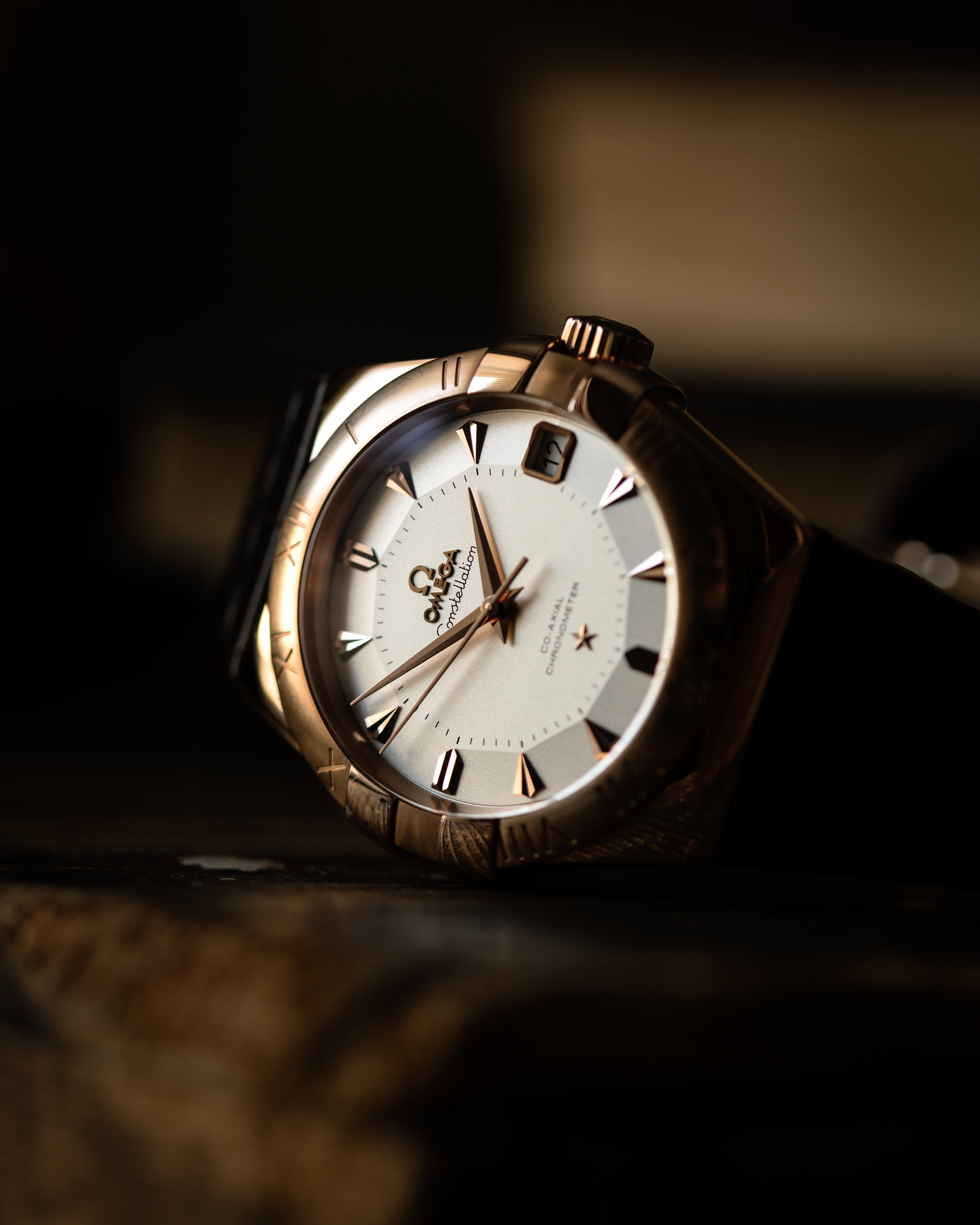 an omega constellation photographed on its side on a wooden base