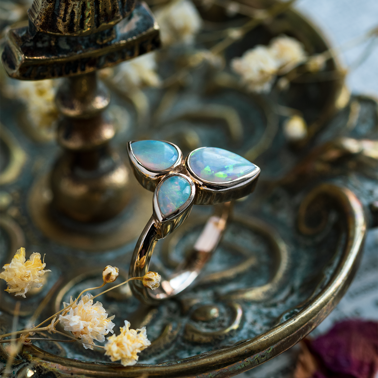 Pear Shape 3 Opal Ring in 9ct yellow gold photographed on a vintage ornament with flowers