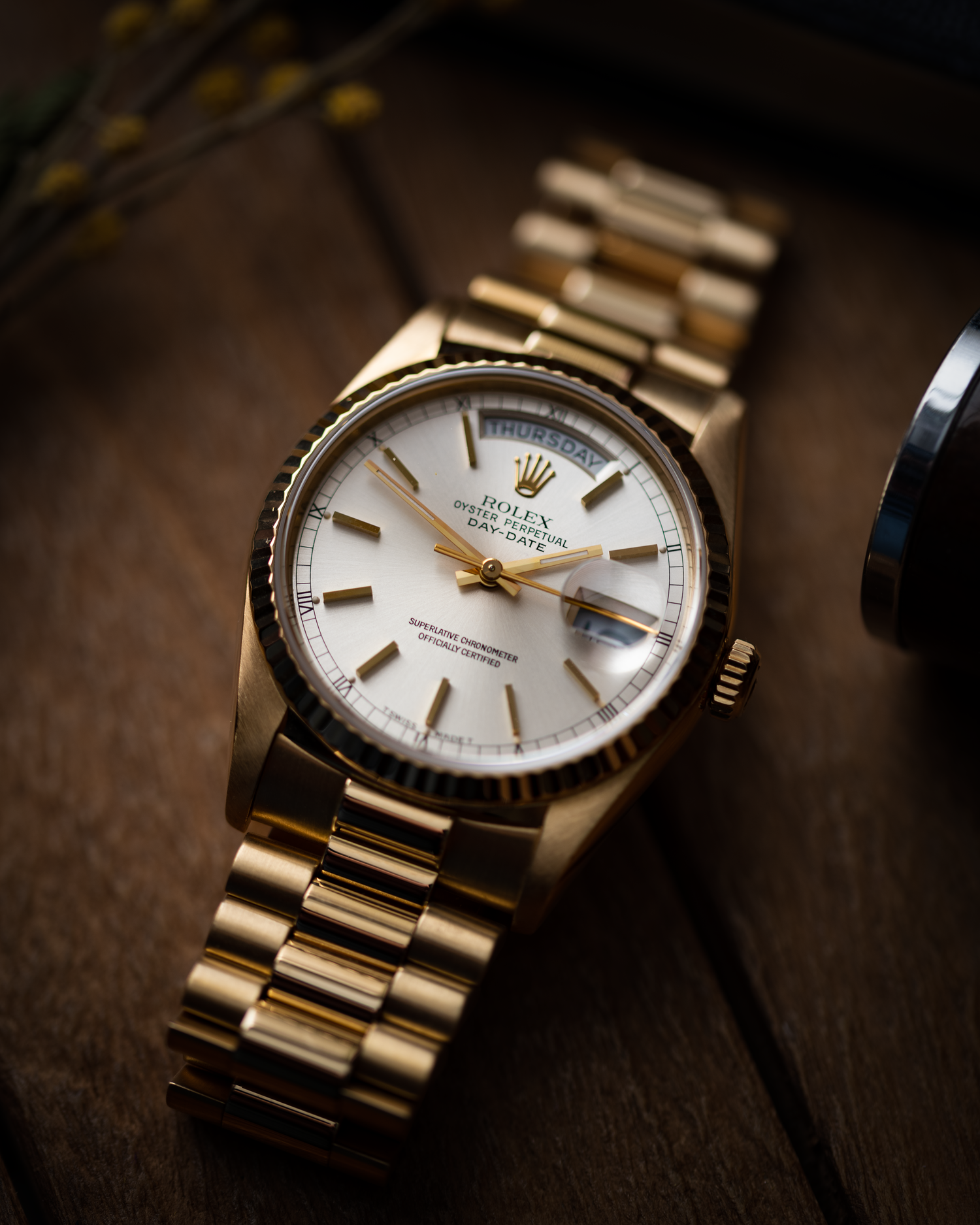 a rolex day date photographed on a wooden base
