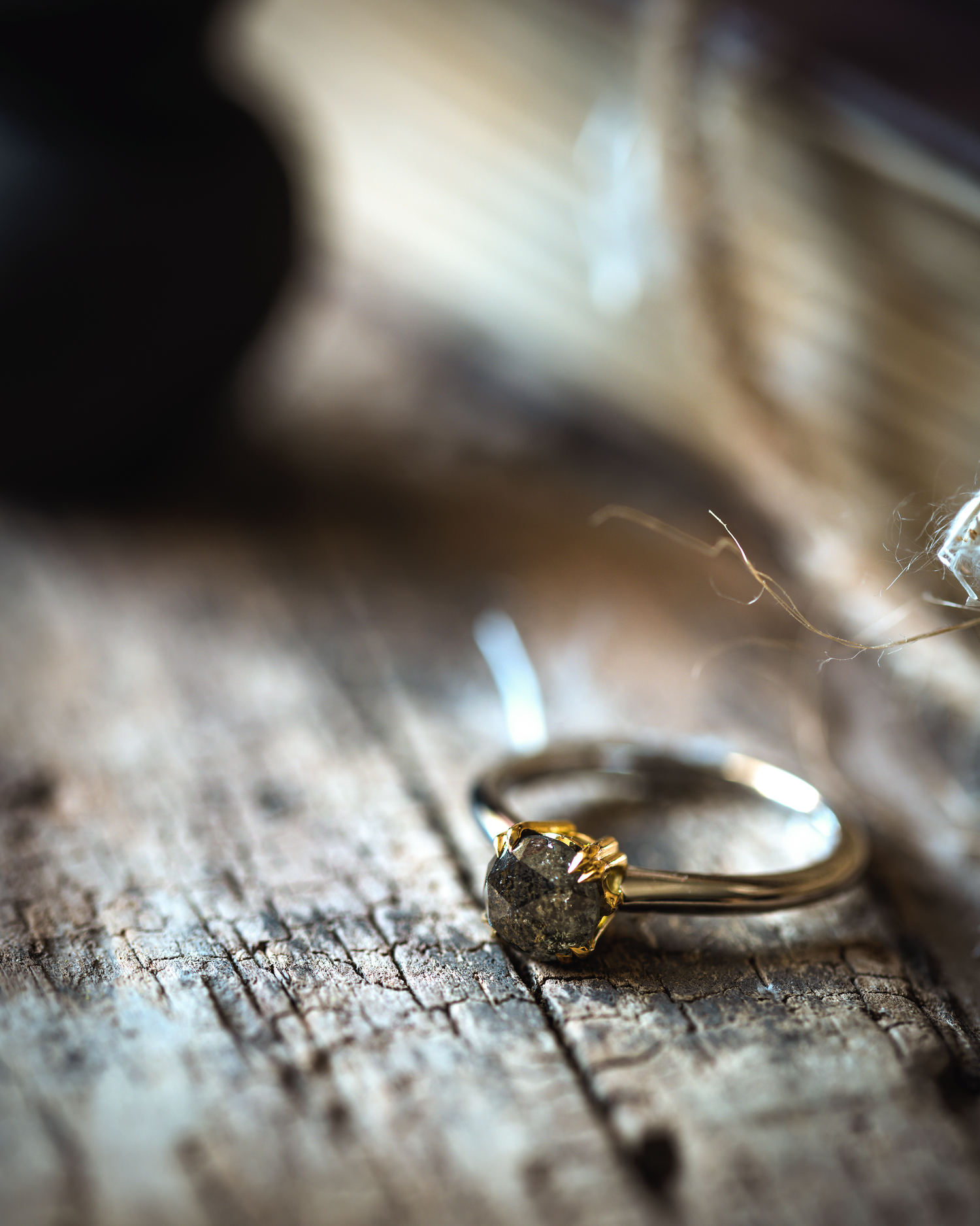 a salt and pepper diamond ring on its side photographed on a wooden base